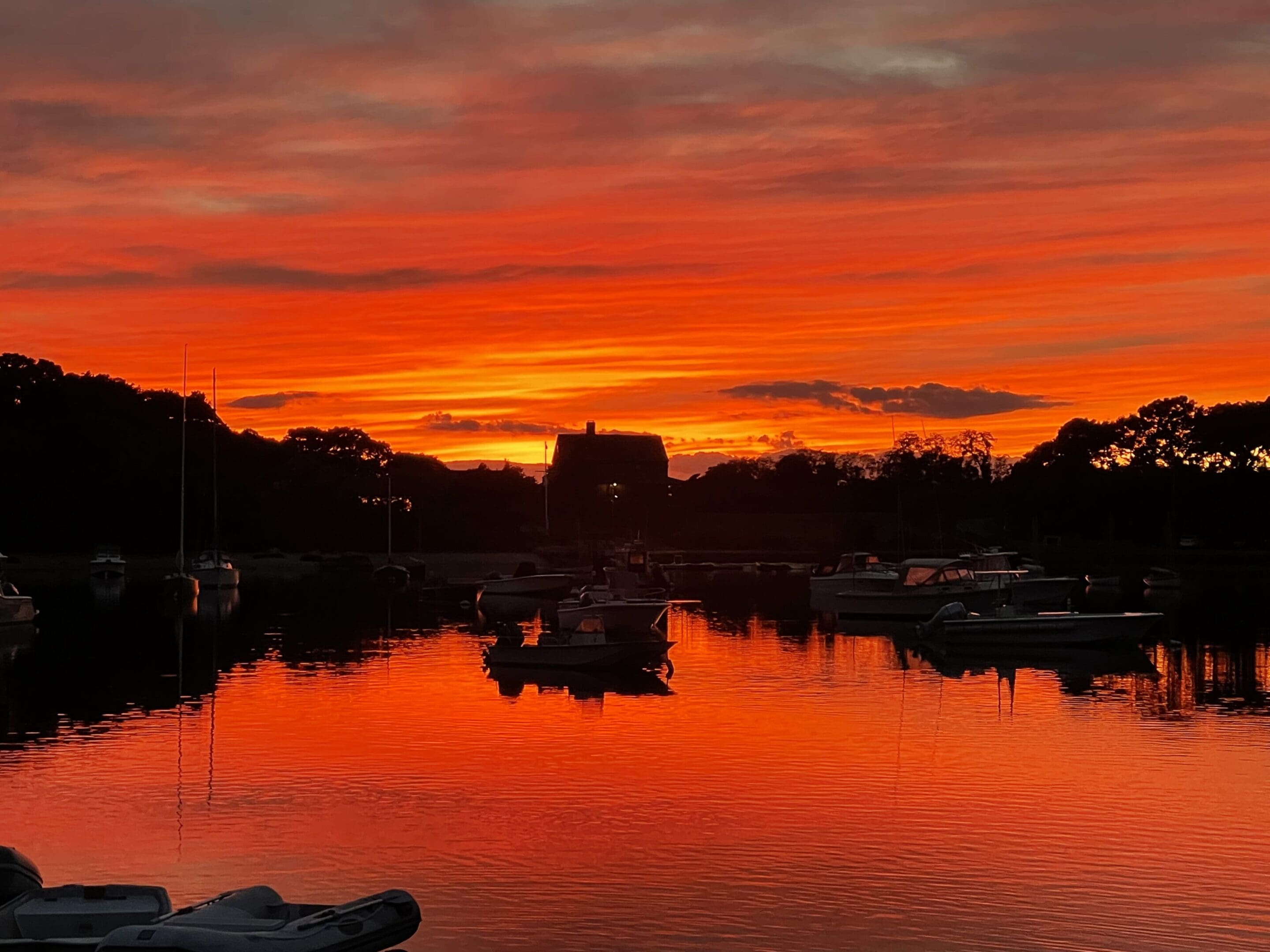 A sunset over the water with boats in it.